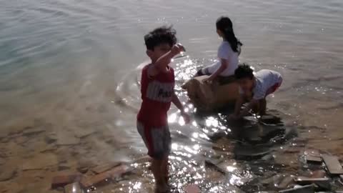 These kids are making a castle out of beach sand, a lake trip