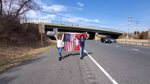 2 women on the side of the road showing there support for the trucker convoy