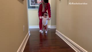 Mom helps baby dance to rock n roll song down the hall