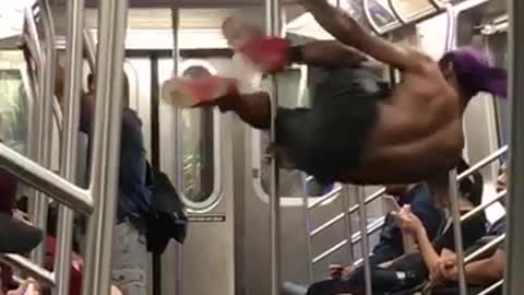Shirt guy black shorts purple bandana dancing on pole subway