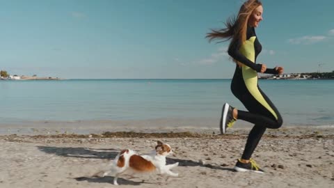 Young adult athletic woman running with dog near sea