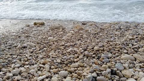 close up waves hit beach stones 1