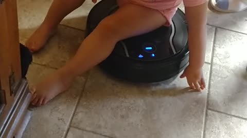 Baby riding the robot vacuum