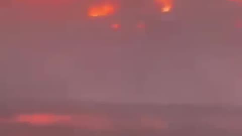 People in a swimming pool in Maui as fires rage all around.