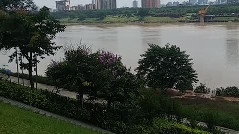 I like the beauty of the riverside, blue sky, white clouds, grass, trees, flowers