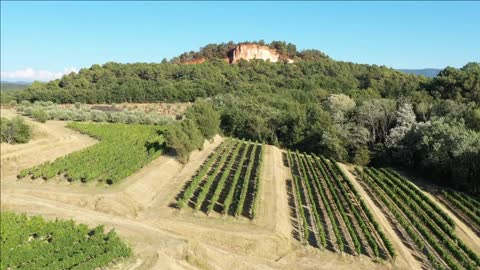 aerial sunny day over vineyards fields and ochre quarries roussillon village france vaucluse luberon