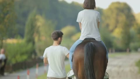 Young couple having fun on weekends. A girl riding a horse with her boyfriend