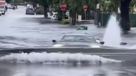 Cars drive across stagnant water roads.