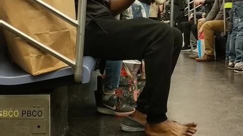 Shoeless man purells hands and feet on subway