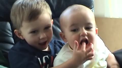 Baby sucking his brother's finger