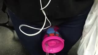 Pink cup between legs spilling onto subway floor
