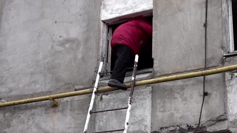 Ukrainians use ladders to reach damaged homes