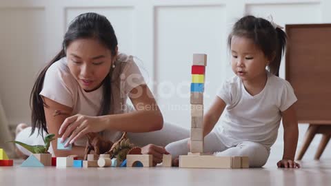 Asian mum playing with daughter building