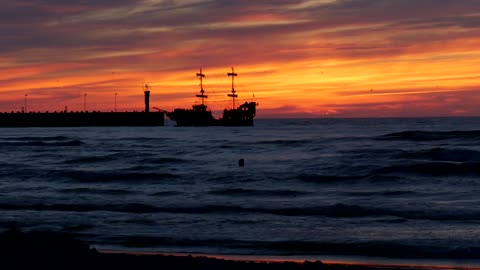 Sunset on a beach with people and a boat in the sea