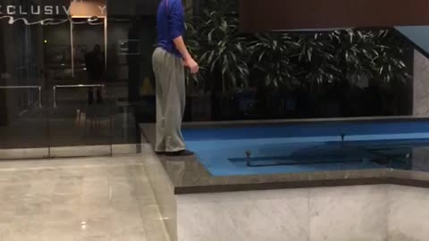 Teen in blue shirt tries to jump to stair rail and falls in water
