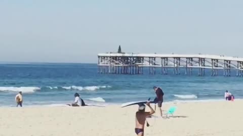 Guy in speedo balancing surfboard on head