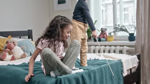 kids playing their cat in the bedroom