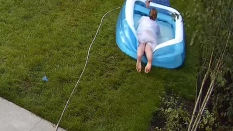 2 chicks struggle and fall in trying to empty a kids pool.