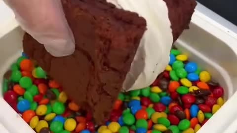 The cake is topped with cream and dipped in rainbow candy. Do you want to eat it?
