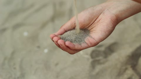 Person passing sand from one hand to another