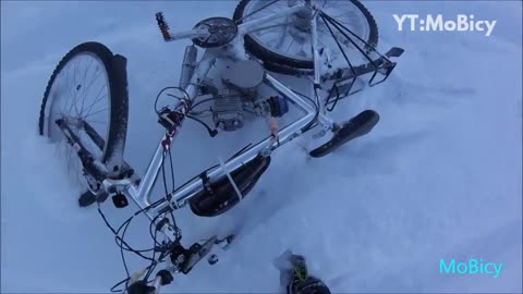 Gloved hands falls off motorized bicycle in snow field