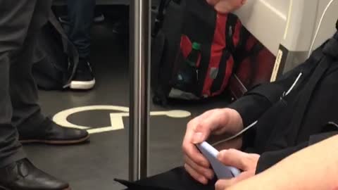 Woman rests her bare feet on her backpack on subway train