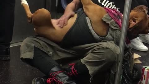 Guy on subway holds brown dog on back and rubs its belly