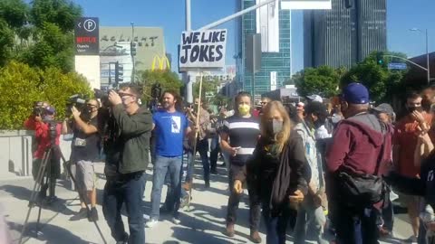 Netflix workers outraged by Dave Chapelle’s comedy special walk off the job. They are met by counter-protesters with signs that say “Jokes are funny”.