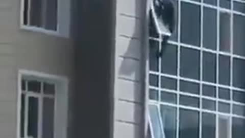 Hero climbs out his 8th floor window to save 3 year old hanging out of a window above!