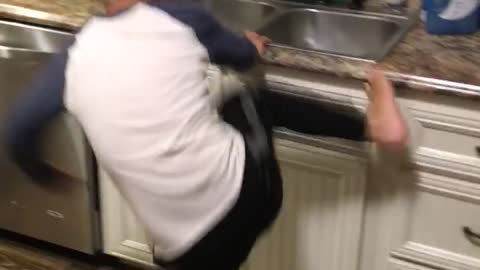 Kid boy runs to kitchen tries to kick leg onto sink hits leg instead