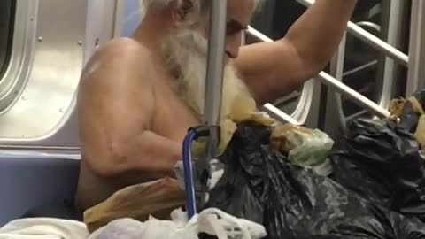Shirtless homeless man applying on lotion in subway train