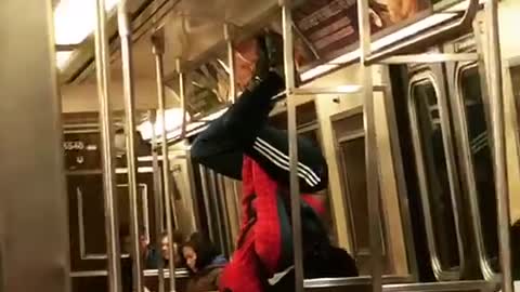 Man in spiderman outfit hangs from subway ceiling