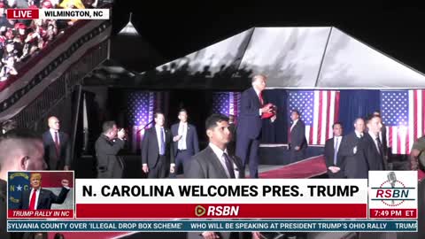 Trump throws MAGA hats to the audience as he takes the stage in North Carolina.