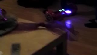 Girl in white shirt and glasses falls backwards on red hoverboard