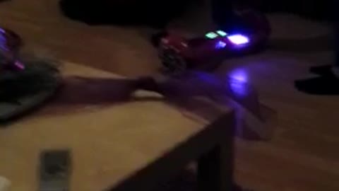 Girl in white shirt and glasses falls backwards on red hoverboard