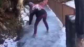 Girl in purple jeans next to waterfall slips on ice and hits rail