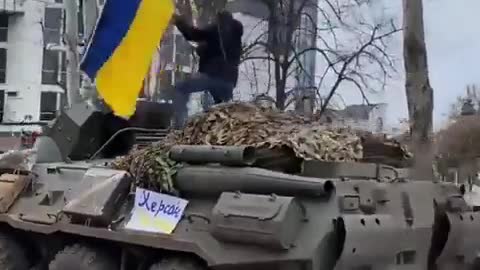 A Ukrainian climbed onto a Russian military tank and raised the Ukrainian flag on it.