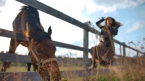 Stylish lady adjusting hair near eating horse