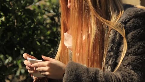 Girl with red long hair blowing her nose with a napkin