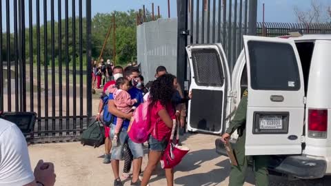 Migrants being walked through the border gate