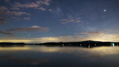Night sky with stars at a calm lake, time lapse