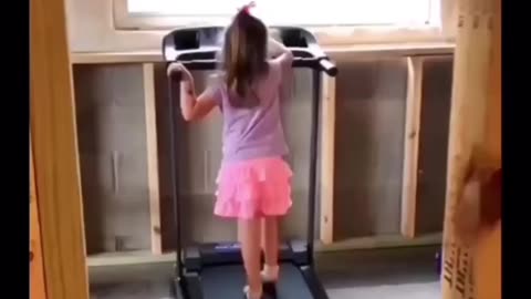 Little girl teaches cute pet cat, how to use treadmill