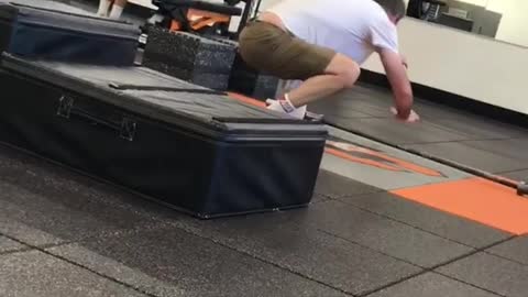 Balding guy in gym practicing how to stand up on surfboard