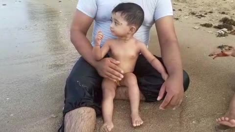 Funny cute baby playing in beach with father