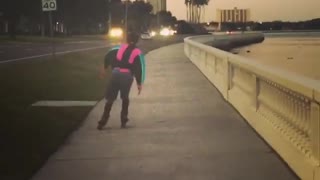 Guy rollerblading down the street in blue and pink windbreaker jacket