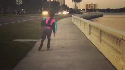 Guy rollerblading down the street in blue and pink windbreaker jacket