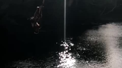 Shirtless guy faceplants in river off rope swing