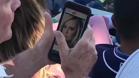 Old man at baseball game swiping on tinder