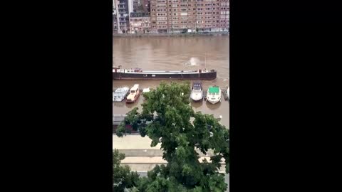 Watch as a barge sinks in a flooded Belgian river