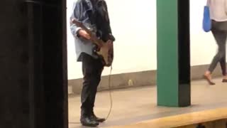 Guy denim jacket playing electric guitar subway